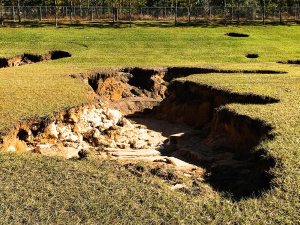 A sinkhole in the yard, showing settling soils